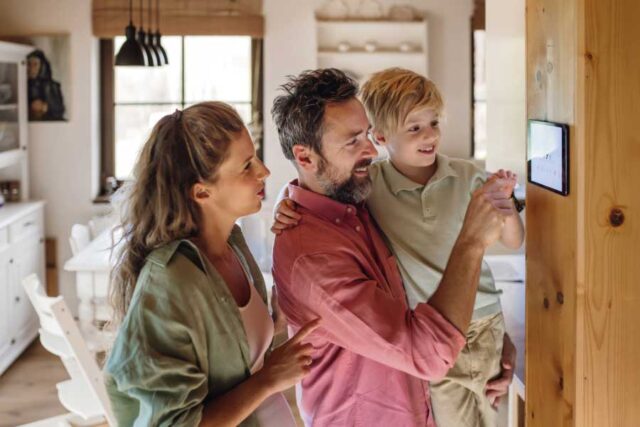 Happy family adjusting a smart home panel in a bright, cozy kitchen.