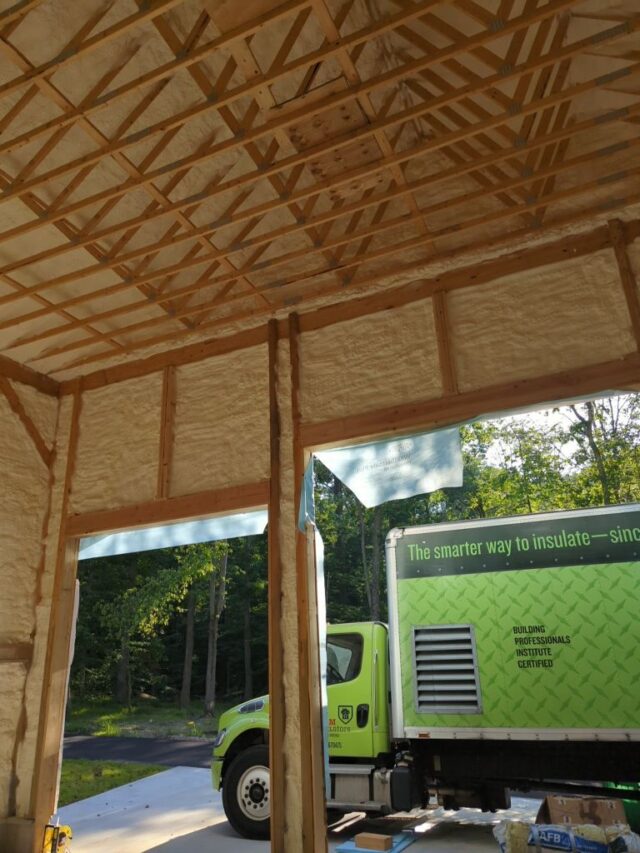 Green Foam InSEALators truck parked outside of a large garage with spray foam insulation.