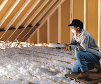 Worker spraying blown in fiber glass in an attic
