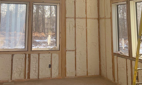 Exterior wall spray foam insulation in multi-window room.