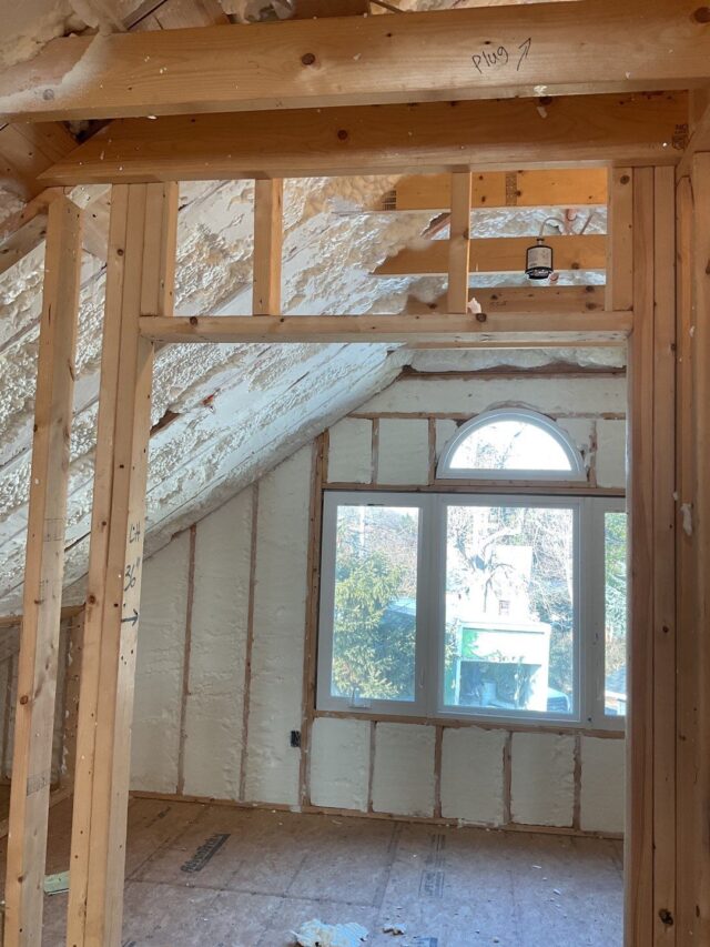 Insulation in the ceiling and walls of an attic with a window.