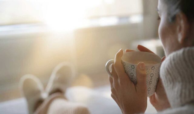 Woman sipping warm drink from a mug on a sunny winter morning.